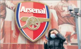  ?? REUTERS ?? ■
A woman wearing a mask walks past Arsenal’s Emirates Stadium on Friday.