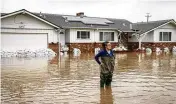  ?? ASSOCIATED PRESS ?? Colleen Kumada-McGowan surveys the scene while standing in flood waters from huge amounts of rain in front of her home near San Francisco.