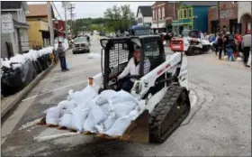  ?? DAVID CARSON — ST. LOUIS POST-DISPATCH VIA AP ?? A bobcat moves a pile of sandbags to be stacked on South Central Avenue in Eureka, Mo., to protect businesses from the rising floodwater of the Meramec River on Monday. Torrential rain caused Missouri waterways to burst their banks over the weekend...