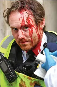  ??  ?? An injured police officer receives treatment yesterday in Whitehall, near where protesters daubed graffiti on the statue of Churchill, left