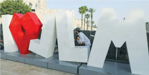  ?? (Marc Israel Sellem/The Jerusalem Post) ?? A FAMILY SHELTERS behind the ‘I love Jerusalem’ sign as Hamas fired rockets on the capital on May 10.