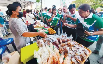  ?? / HONEY COTEJO ?? MANDAUE DELICACIES. Mandaue City Mayor Jonas Cortes (third from right) checks one of the stalls selling local delicacies at the Mandaue Food Market, which opened during the city’s fiesta kickoff on Sunday, May 1, 2022. With Cortes were (from left) City Councilor Cynthia Remedio, Vice Mayor Glenn Bercede and City Councilor Nerissa Soon-Ruiz.