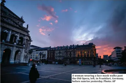  ?? Photo: AP ?? A woman wearing a face mask walks past the Old Opera, left, in Frankfurt, Germany, before sunrise yesterday.