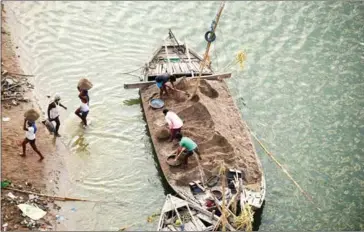  ?? SAVANN OEURM/OXFAM ?? Indian workers use boats to transport sand as they remove it from the River Yamuna in Allahabad. Amid growing outrage over the latest murder of a journalist in India, police have arrested a truck driver accused of killing Sandeep Sharma over his...