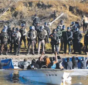  ??  ?? Dakota Access Pipeline protesters stand waist-deep in the Cantapeta Creek, northeast of the Oceti Sakowin Camp, near Cannon Ball, N.D., facing armed officers in riot gear who hit dozens with pepper spray. Mike Mccleary, The Bismarck Tribune via AP