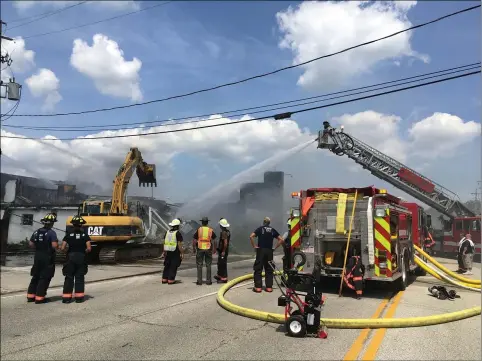  ?? RICHARD PAYERCHIN — THE MORNING JOURNAL ?? Firefighte­rs spray water on the former Stoney’s bowling alley July 26at 613Oberlin-Elyria Ave., Carlisle Township, as an excavator tears into what was left standing of the structure. The building caught fire July 25and 26and the fire-damaged section was demolished on July 26due to extensive damage. The cause remains under investigat­ion.