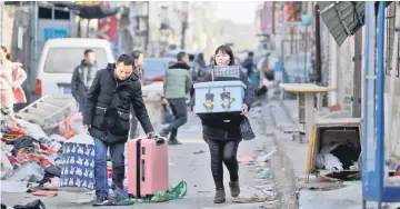  ?? — Reuters photo ?? A couple leave with their belongings after they were required to move out due to a citywide fire safety inspection prompted by a deadly fire in an apartment block, at Xinjiancun in Daxing district, in Beijing.
