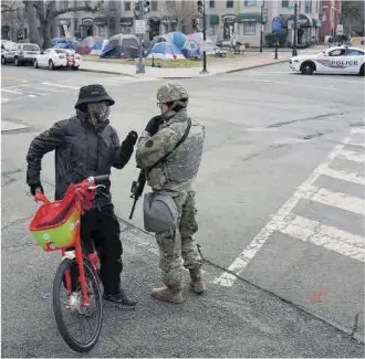  ?? Nathan Howard / Getty Images / AFP ?? Un ciclista conversa amb un membre de la Guàrdia Nacional a prop del Capitoli, ahir.