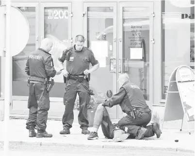  ?? — Gambar Reuters ?? SUSPEK yang terlentang di kaki lima dikerumuni pegawai polis sejurus menikam beberapa mangsa di Dataran Pasar di Turku, pada Jumaat.