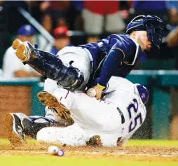  ??  ?? MILWAUKEE BREWERS catcher Manny Pina (top) hold on to the ball as he tags out Texas Rangers baserunner Jonathan Lucroy at home plate in the sixth inning of the Rangers’ 6-4 home victory on Tuesday night.
