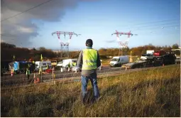  ?? (Stephane Mahe/Reuters) ?? A MAN in a yellow vest watches cars camped along a road near the Nantes Atlantique Airport in Bouguenais yesterday.