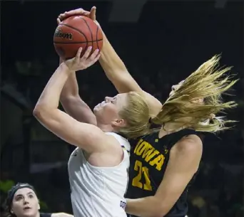  ?? Michael Caterina/South Bend Tribune ?? OUT OF NOWHERE Iowa’s Hannah Stewart rises from behind all that hair to block a shot by Notre Dame’s Abby Prohaska Thursday night in Notre Dame, Ind. The No. 1-ranked Fighting Irish routed No. 14 Iowa, 105-71, behind 30 points from Arike Ogunbowale.