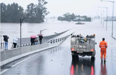  ?? MARK BAKER AP ?? An emergency vehicle blocks access to the flooded Windsor Bridge on the outskirts of Sydney, Australia, on Monday.