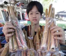  ?? ?? Cozzey Viveljisti­n, 13, shows sticks of tuhau used to make the traditiona­l side dish of Kadazandus­un, which his family sells at the Donggongon market. Tuhau is a type of wild ginger native to the jungles of Sabah.