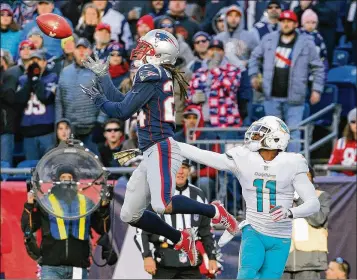  ?? JIM ROGASH / GETTY IMAGES ?? The Patriots’ Stephon Gilmore intercepts a pass intended for DeVante Parker during the second quarter of the Dolphins’ 35-17 defeat at New England, where they have dropped nine in a row.