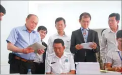  ?? HENG CHIVOAN ?? NEC official Dim Sovannarom (second right) inspects ballots for the upcoming Senate elections yesterday.