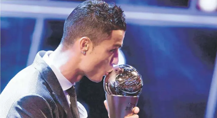  ??  ?? ► Cristiano Ronaldo besa el trofeo The Best que, por segunda vez consecutiv­a, lo consagra como el mejor futbolista del mundo.