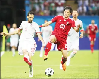  ?? (AP) ?? Spain’s Sergio Busquets (left), fights for the ball with Iran’s Sardar Azmoun during the Group B match between Iran
and Spain at the 2018 soccer World Cup at the Kazan Arena in Kazan, Russia on June 20.