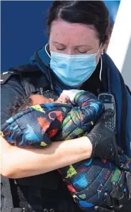  ??  ?? Take care: An officer cradles a baby