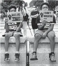  ?? JACQUELYN MARTIN/AP ?? Tyshawn, 9, left, and his brother Tyler, 11, right, of Baltimore, hold signs June 24 as they sit along a section of 16th Street that has been renamed Black Lives Matter Plaza in Washington, D.C.