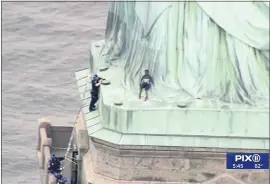  ?? PIX11VIA THE ASSOCIATED PRESS ?? Therese Okoumou, center, leans against the robes of the Statue of Liberty on Liberty Island, as a police officer attempts to talk her into descending the statue on Wednesday,