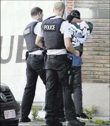  ?? VIRGINIA MAYO/THE ASSOCIATED PRESS The Associated Press ?? Police officers check the identifica­tion of a man near the police headquarte­rs in Charleroi, Belgium, after a machete attack in the area on Saturday. A man attacked two police officers near the headquarte­rs before being shot and killed.