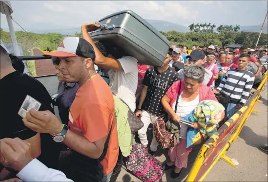  ?? Fernando Vergara Associated Press ?? VENEZUELAN­S cross the Simon Bolivar Internatio­nal Bridge into Colombia in February. An average of 35,000 people cross it every day, and half return to Venezuela.