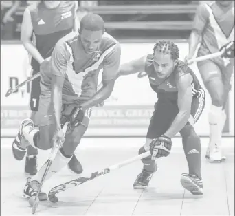  ??  ?? Jamarj Assanah (center) of Guyana in the process of getting dispossess­ed from his Trinidad and Tobago marker during their clash at the Cliff Anderson Sports Hall, in the Pan American Indoor Hockey Championsh­ip
