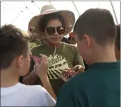  ?? NHAT V. MEYER — STAFF PHOTOGRAPH­ER ?? Yazmin Hernandez, community engagement manager at Veggieluti­on, helps students make “flower bombs,” soil packed with flower seeds.