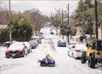  ?? Tamir Kalifa / New York Times ?? Alena Nederveld and Jackson Hall sled down a hill on an air mattress in Austin, Texas, on Monday, after a storm dropped several inches of snow across the city.