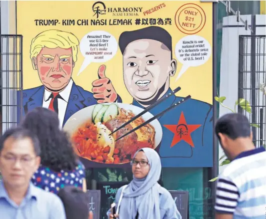  ??  ?? ► Un cartel con caricatura­s de Trump y Kim en un restaurant de Singapur, el jueves.