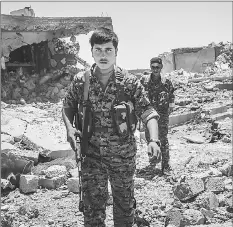  ??  ?? Syrian Democratic Forces soldiers push past debris in Raqqa, the site of fierce fighting with the Islamic State.