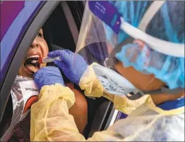  ?? Brian van der Brug Los Angeles Times ?? A MEDICAL WORKER swabs a person’s mouth for COVID-19 testing in Boyle Heights this week. City-run test sites reportedly tripled their workload Thursday.