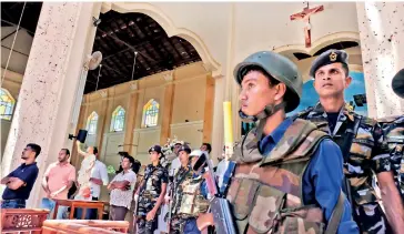  ??  ?? Security personnel stand guard amidst the crowd at St Sebastian's Church, Katuwapiti­ya after the attack