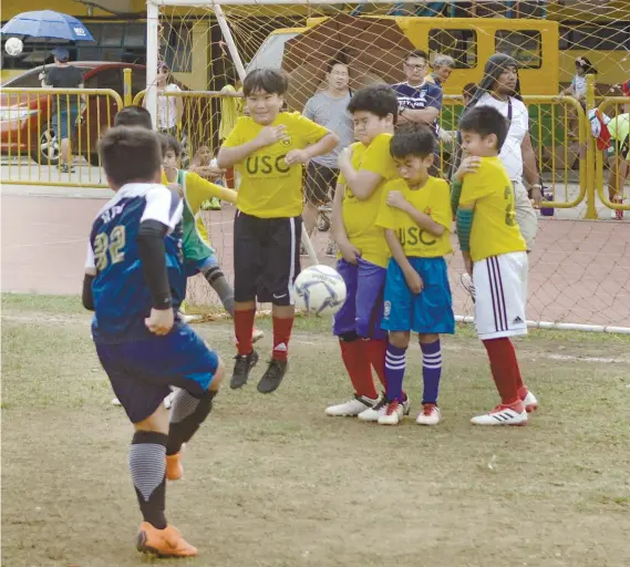  ?? SUNSTAR FOTO / ARNI ACLAO ?? BEND IT. A player from Paref Springdale tries to get past the wall put up by the University of San Carlos during their match in the Sinulog Football Festival.