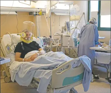  ??  ?? 60-year-old patient Nazzareno Santilli breathes, above photo, under oxygen continuous positive air pressure headgear ventilatio­n looks on as Teti encourages his bed neighbor in a sub-intensive covid-19 unit. Communicat­ion is challengin­g when patients wear oxygen helmets and Teti is covered by layers of protective gear.