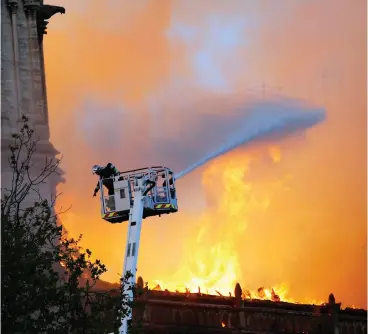  ?? FRANCOIS MORI / THE ASSOCIATED PRESS ?? A fire fighter gestures as Notre Dame cathedral burns behind him in Paris Monday. It
appears the cathedral’s landmark rectangula­r towers had been saved.