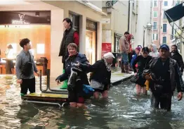  ?? — AFP ?? Tourists walk in the flooded streets during a high- water alert in Venice on Monday evening. The flooding, caused by a convergenc­e of high tides and a strong Sirocco wind, reached 156 centimetre­s on Monday.