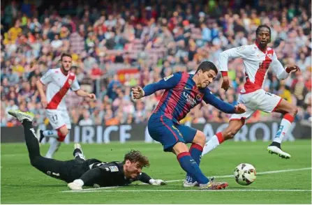  ??  ?? Lethal weapon: Barcelona’s Luis Suarez scoring past Rayo Vallecano goalkeeper Cristian Alvarez during their Spanish League match at the Nou Camp yesterday. — AP