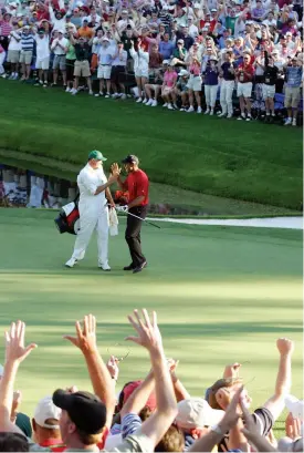  ??  ?? Tiger Woods and his caddie celebrate after his birdie on the 16th hole during the final round of The Masters, 2005