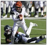  ?? (AP/Jay LaPrete) ?? Cincinnati quarterbac­k Joe Burrow runs out of the tackle of Tennessee’s Jadeveon Clowney during the first half Sunday in Cincinnati. Burrow, who had no turnovers or sacks for the first time this season, passed for 249 yards and two touchdowns to key a 31-20 victory for the Bengals. More photos at arkansason­line.com/112seahawk­s/