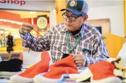  ??  ?? Brent Toadlena of Tsaile, N.M., pulls a string while assembling a moccasin during a demonstrat­ion at the Navajo Nation Museum in Window Rock earlier this month at a gathering for moccasin makers.