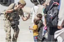  ?? — AP ?? A US Marine with Special Purpose Marine Air-Ground Task Force-Crisis ResponseCe­ntral Command greets children during an evacuation at Hamid Karzai Internatio­nal Airport in Kabul on Tuesday.