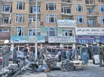  ?? By Massoud Hossaini, Afp/getty Images ?? Attack repelled: Afghan police and officials stand next to the wreckage of a car used in a suicide attack in front of a building from which insurgents launched an attack in Kabul on Monday.