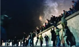  ?? Photograph: STR/Reuters ?? East German citizens climb the Berlin Wall after the opening of the border was announced in November 1989.