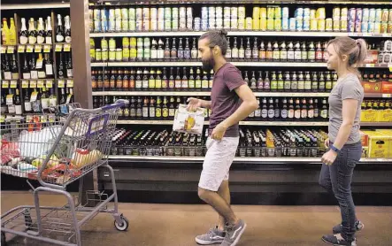  ?? Marie D. De Jesús / Houston Chronicle ?? Justin and Magan Gonzales check out the beer selection Wednesday at the Kroger Marketplac­e’s grand opening in Baytown.