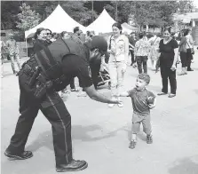  ?? JASON KRYK ?? Amherstbur­g Const. Steve Owen greets a young boy Thursday during the welcoming event at Charles Clark Square in Windsor. Several area police services and other first responders took part in the event.