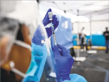  ?? Irfan Khan Los Angeles Times ?? CHERRY COSTALES, a nurse, prepares a COVID-19 vaccine at St. John’s Well Child & Family Center in Los Angeles. California­ns seeking to get a shot are facing numerous hurdles, including convoluted websites, hard-to-reach hotlines and canceled reservatio­ns.