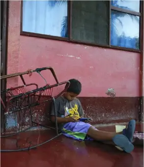  ?? MAYELA lópez/archivo ?? En esta foto de abril del año pasado, Misael Escorcia juega con un celular en el corredor de su casa, en el poblado bananero de Coyol, en Sarapiquí de Heredia.