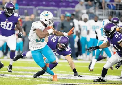  ?? BRUCE KLUCKHOHN/AP ?? Miami Dolphins running back Kenyan Drake tries to break a tackle by Minnesota Vikings linebacker Ben Gideon (42) during the first half of Thursday night’s game in Minneapoli­s.